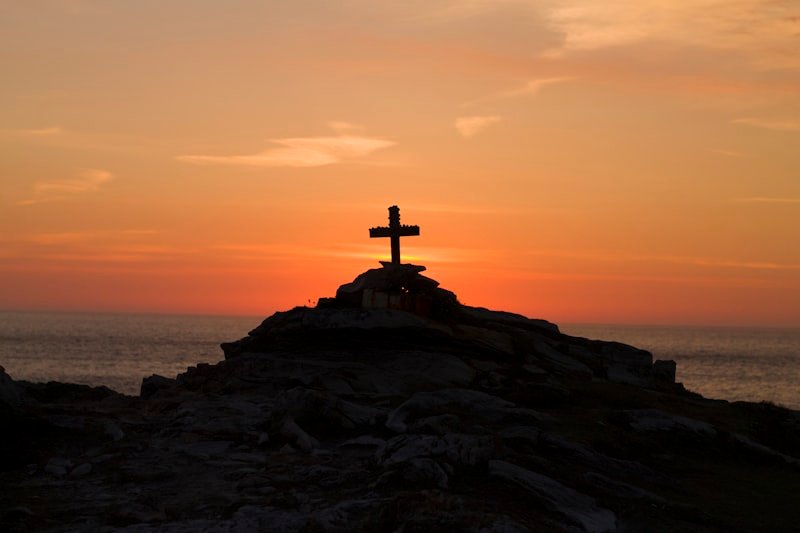 Cross silhouette on a mountain at golden hour